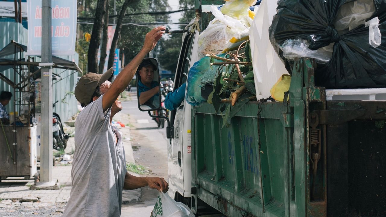 about-us Sanitation worker collects trash from a street in an urban environment, showcasing daily waste management.