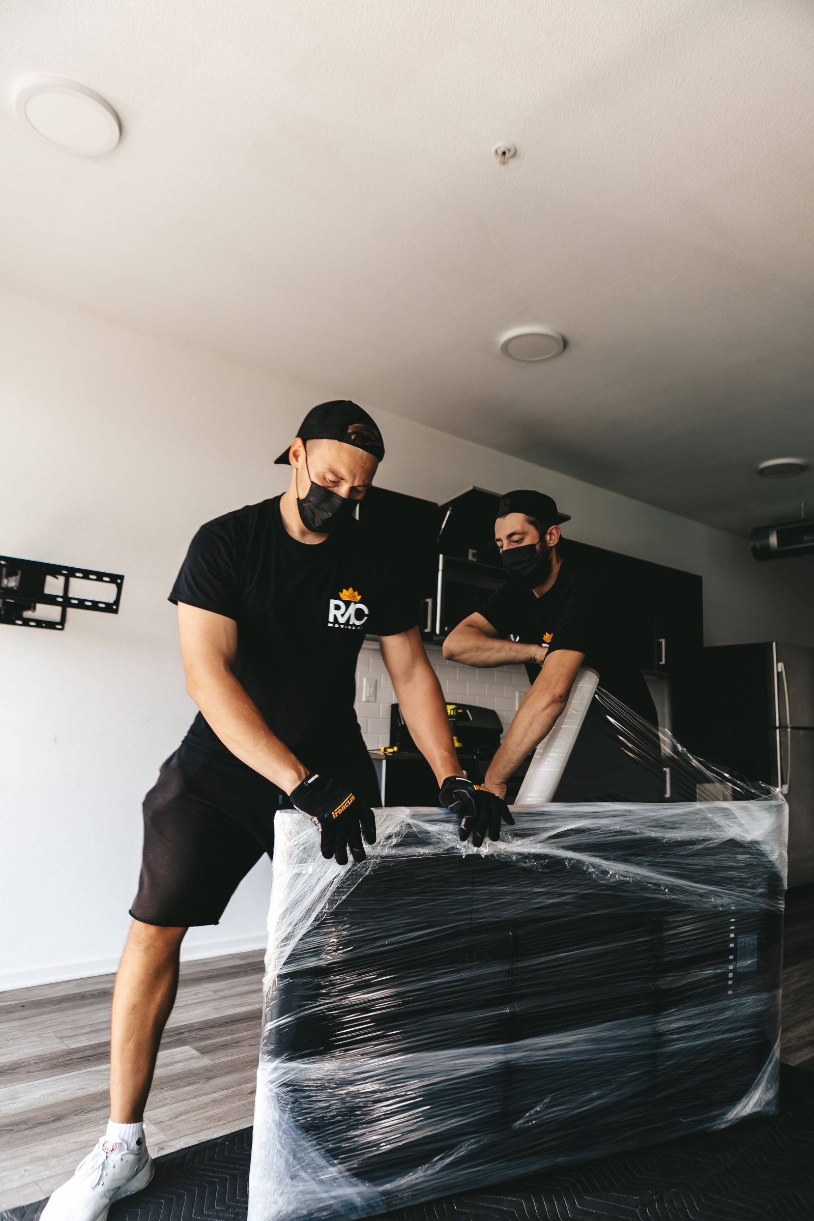 pexels photo 20706505 20706505 Two masked men moving a securely wrapped item in a modern room.
