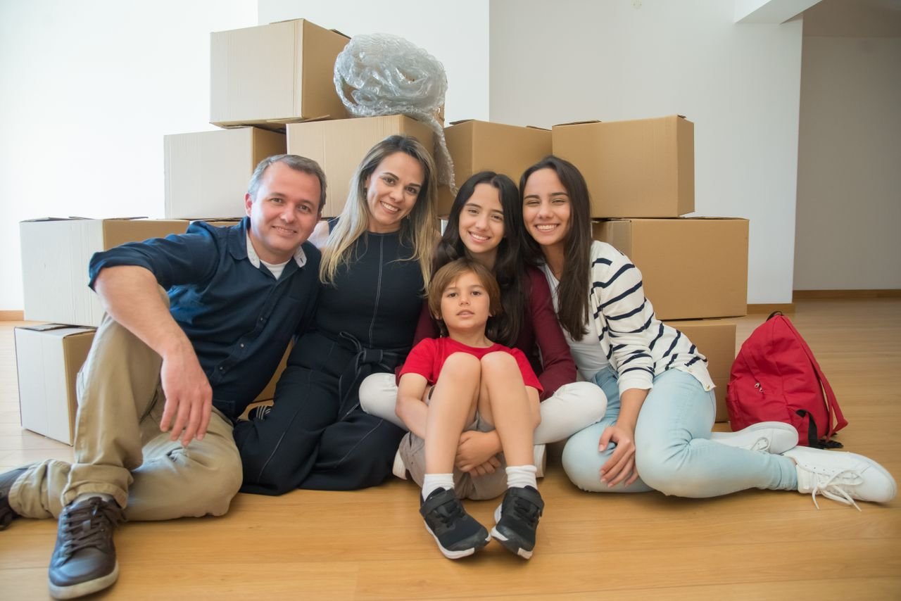 services-01 A joyful family sitting together with moving boxes in their new home.